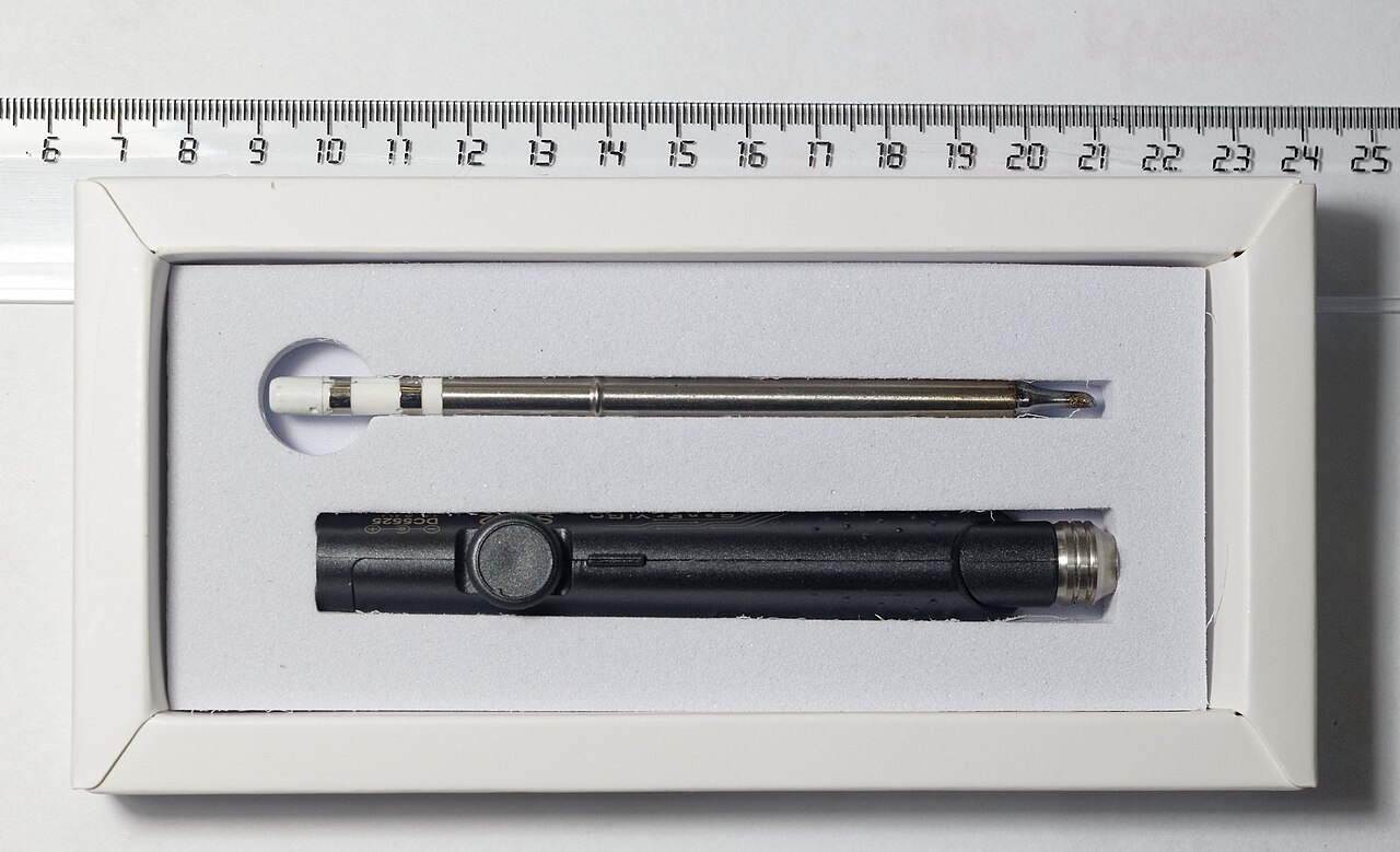 A fine-tipped soldering iron resting in its shipping insert with accessories